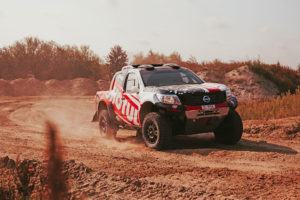 CST Sponsored team BAS AUTO SPORT vehicle in an action shot, kicking up dirt on a turn.