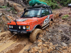 Team 4x4 Malaysia Land Rover off-road vehicle with Land Dragon tires on rough and muddy terrain.