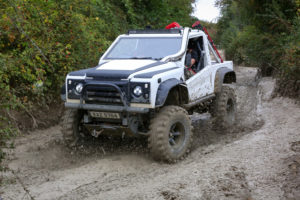 Image of white Land Rover with CST Land Dragon tires in the in the UK, action photoshoot racing through on muddy off-road terrain.